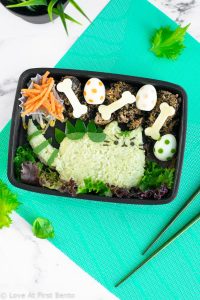 Pusheenosaurus Bento Box - Pusheen the Cat goes prehistoric in this dinosaur themed character bento box! Learn the trick that makes shaping the rice easier, + how to naturally dye your rice green, at www.loveatfirstbento.com