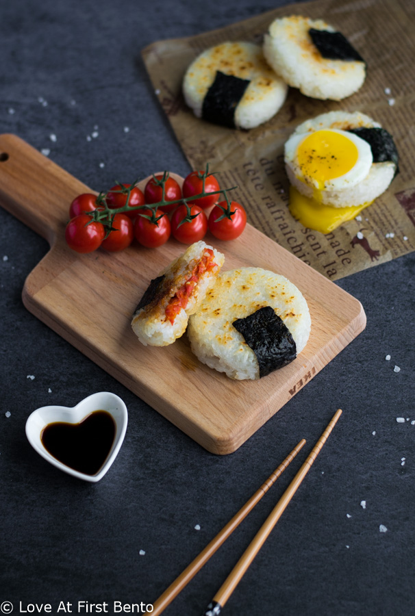 Roasted Tomato Yaki Onigiri with Fried Egg - The ultimate in lunchtime decadence! Toasty golden rice, sweet roasted tomatoes, and a runny fried egg transform your average rice ball into an irresistibly mouth-watering treat! Find out the one common kitchen tool used to make these circular onigiri - I guarantee it's in your kitchen drawers right now! Get this delicious & easy recipe at loveatfirstbento.com | bento box, Japanese food, vegetarian