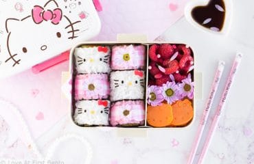 Hello Kitty Sushi Bento - Beautify your lunch with this Hello Kitty Sushi Bento! Filled with adorable Hello Kitty sushi rolls, as well as pink gingham flower sushi rolls, this pretty bento box is an edible dream come true for any Hello Kitty fan! Find out just how easy it is to make by visiting loveatfirstbento.com [character bento, kyaraben, deco sushi]